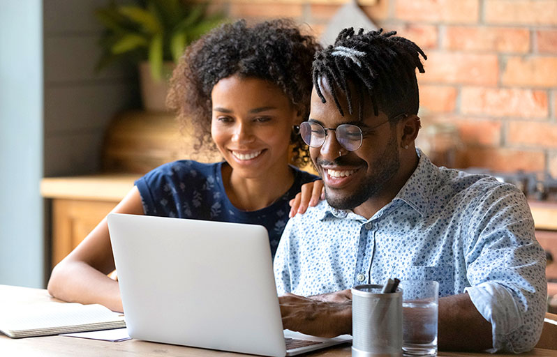 Young couple sitting on couch looking at tablet