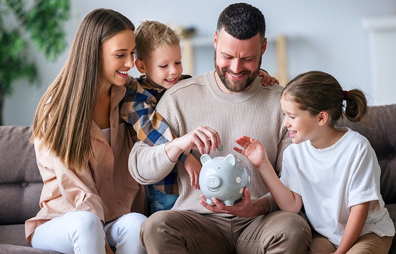 Family putting money in a piggy bank