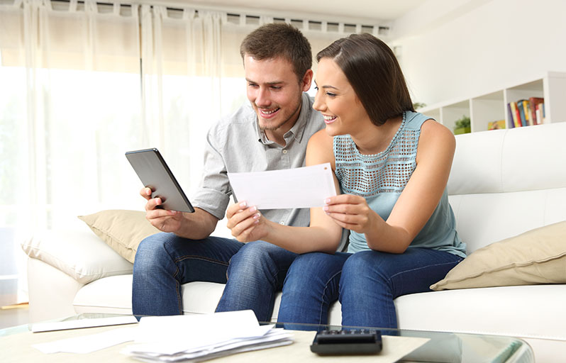 Young couple sitting on couch looking at tablet